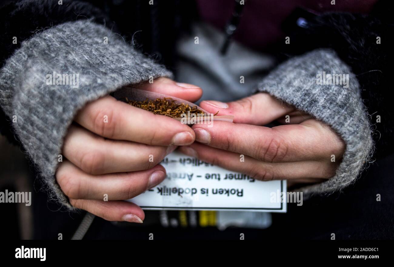 Woman smoking. Close-up of a young woman hand-rolling a cigarette. Stock Photo
