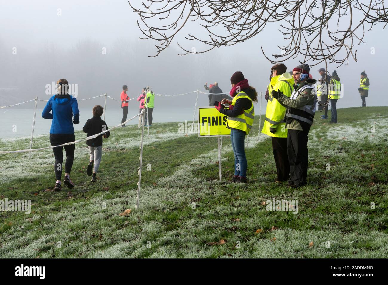 A young runner with an adult finishing at Daventry parkrun, Northamptonshire, UK Stock Photo