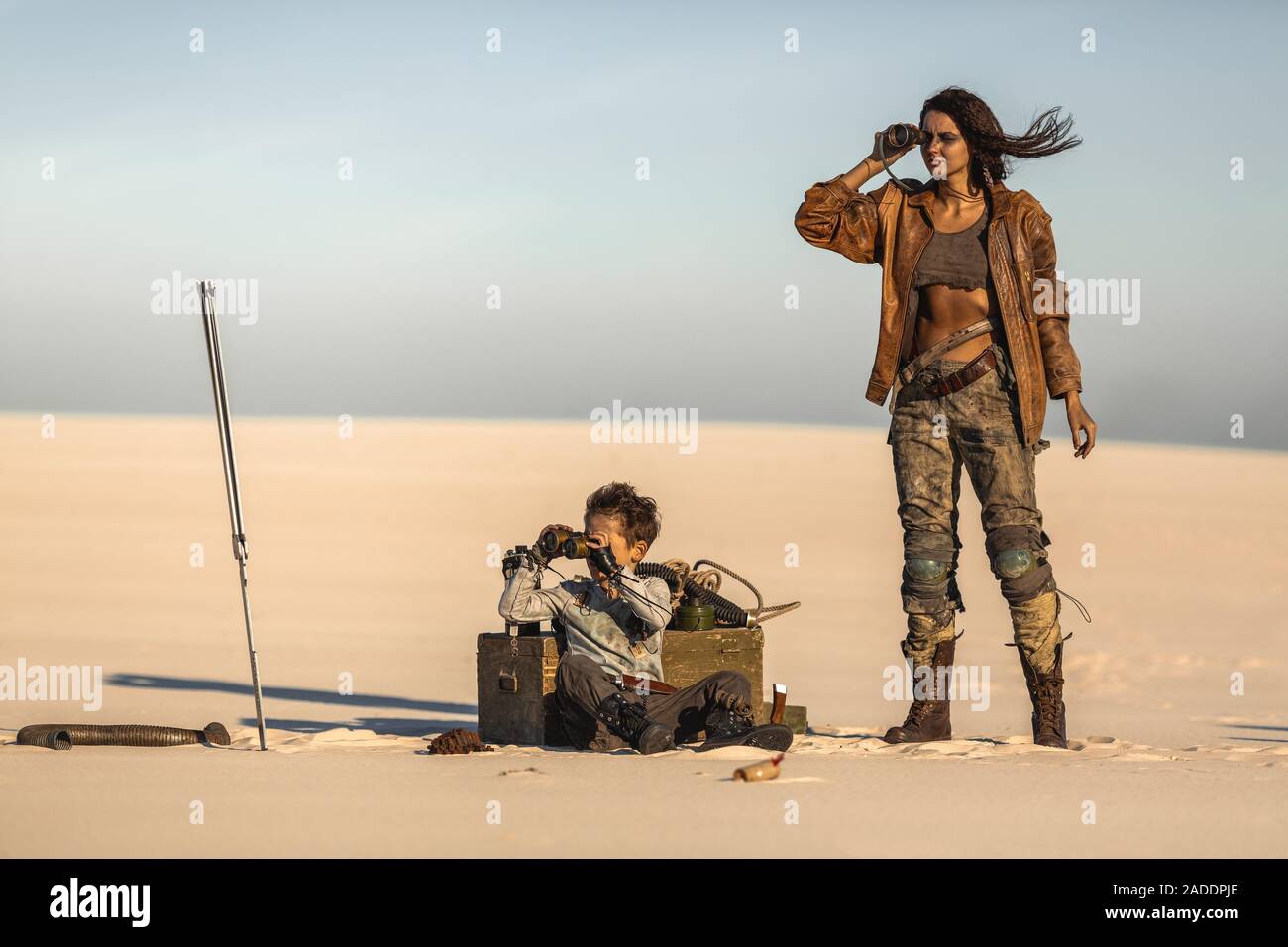 Post apocalyptic hero woman and boy with binoculars outdoors. Desert