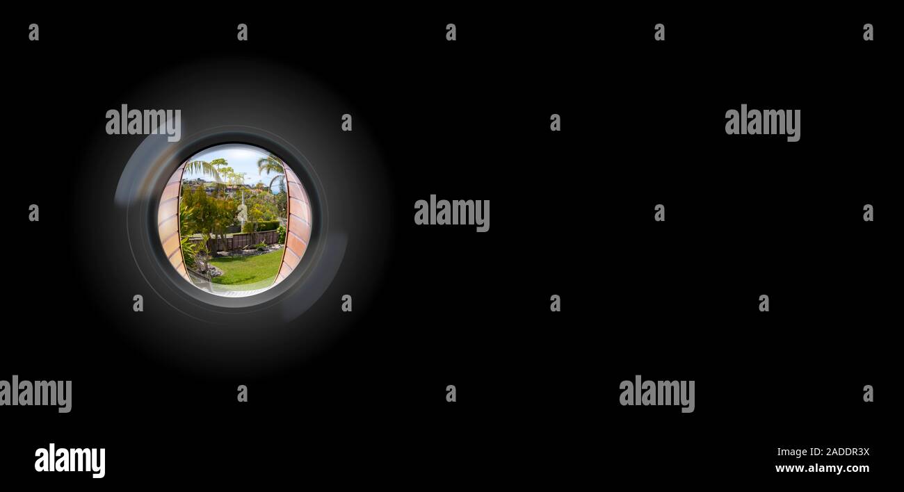 View through peephole in door looking out to entry security surveillance concept solid black background Stock Photo