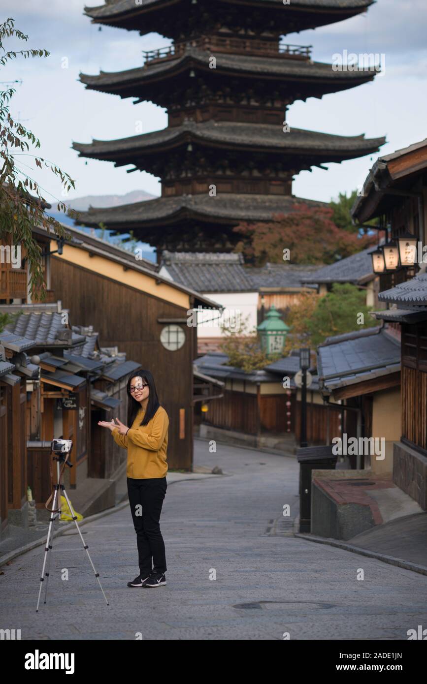 Kyoto, Japan - November 4 2018: An asiatic girl taking a selfie with her camera on a tripod in front of Yasaka Tower, Higashiyama-ku, Kyoto, Japan Stock Photo