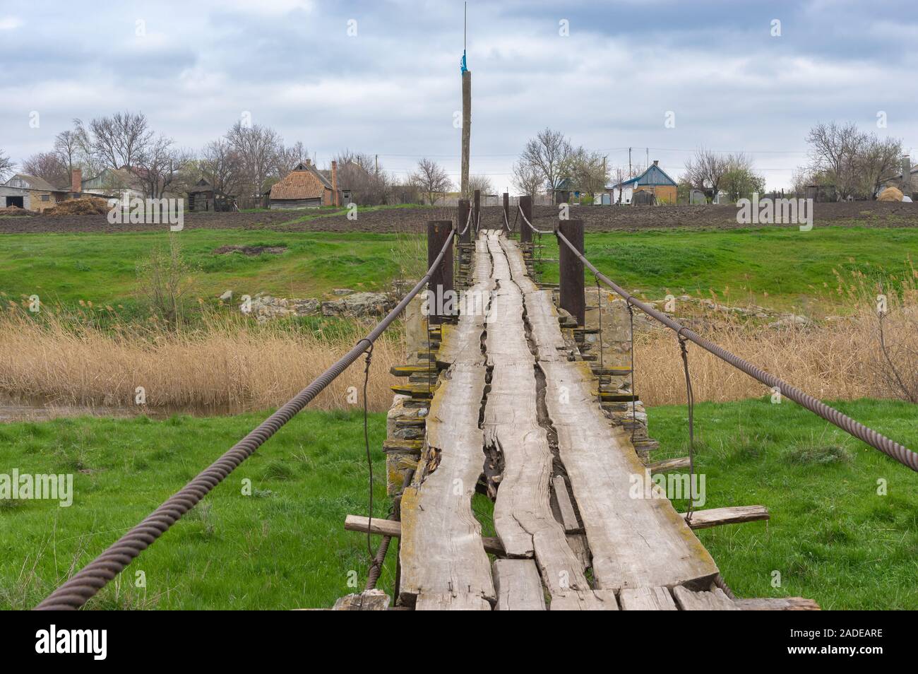 Pedestrian old wooden foot-bridge over small river Tomakivka in Topyla village, central Ukraine Stock Photo