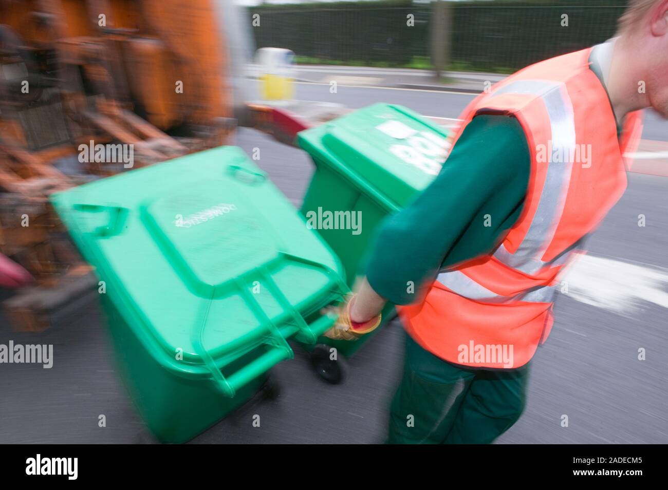 Binman returning neighbourhood wheelie bins after unloading them into