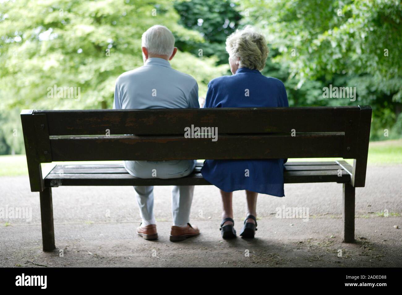 Older couple sitting on a park bench chatting Stock Photo - Alamy