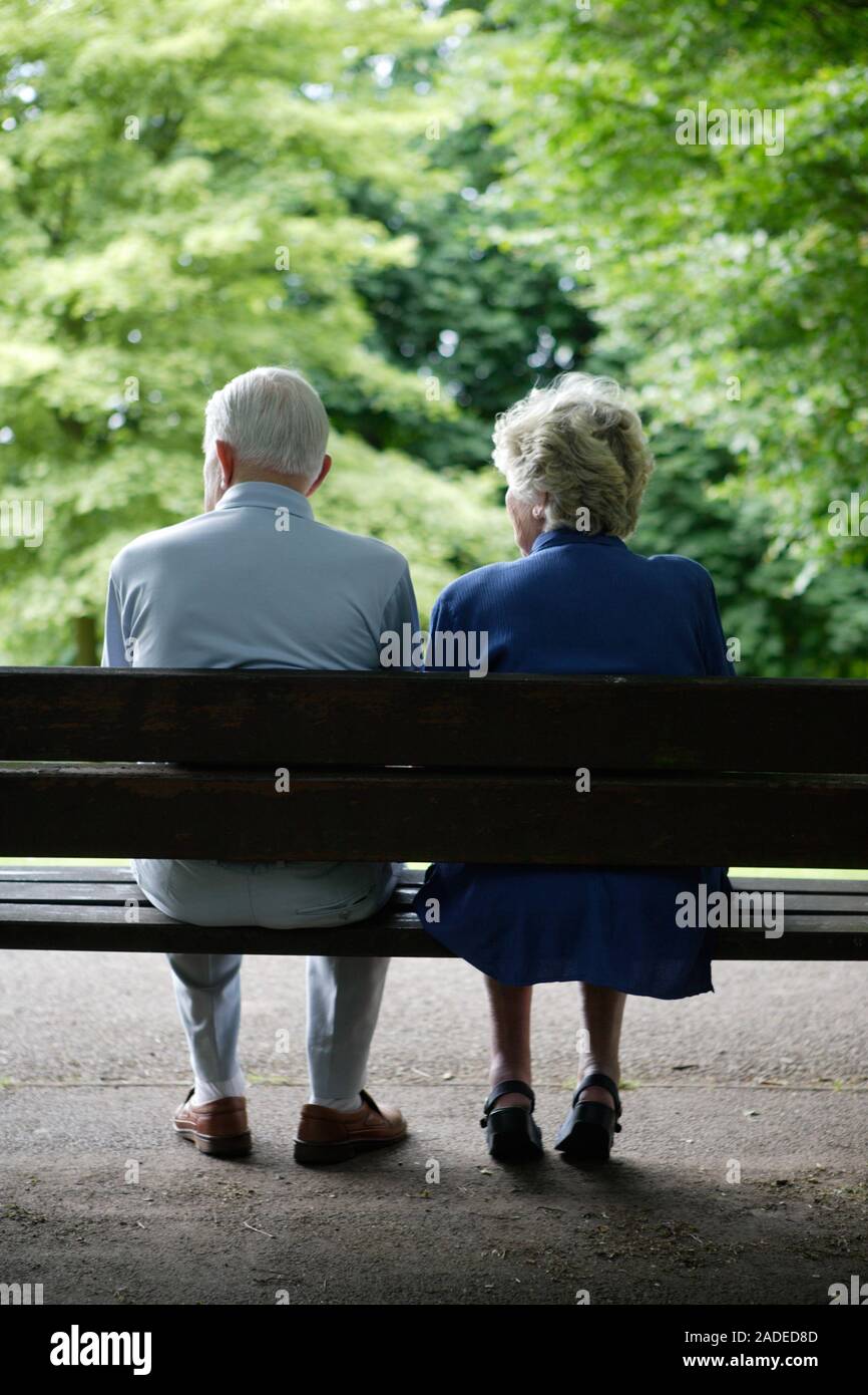 Older couple sitting on a park bench chatting Stock Photo - Alamy