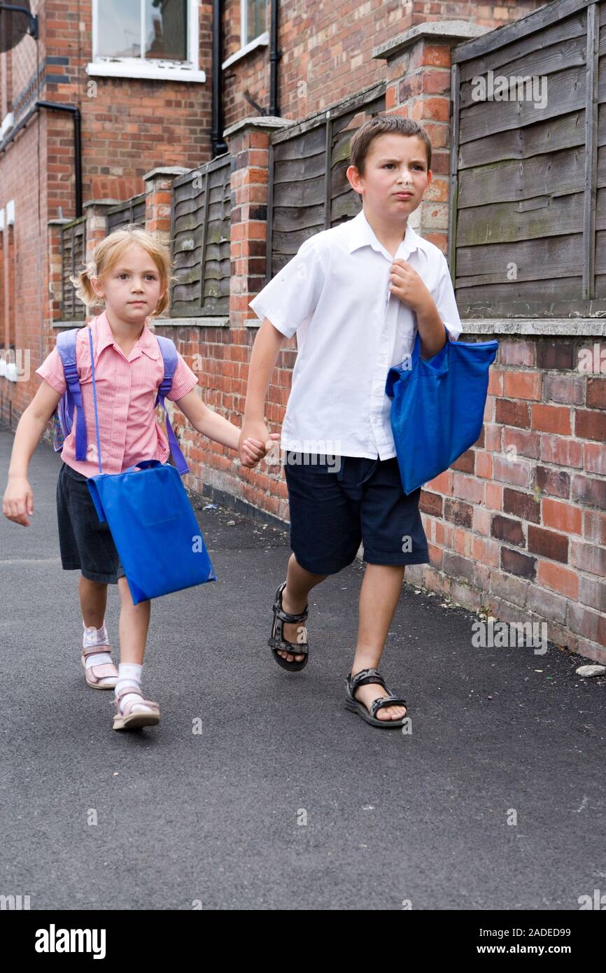 Brother and sister holding hands walking home from school Stock Photo ...