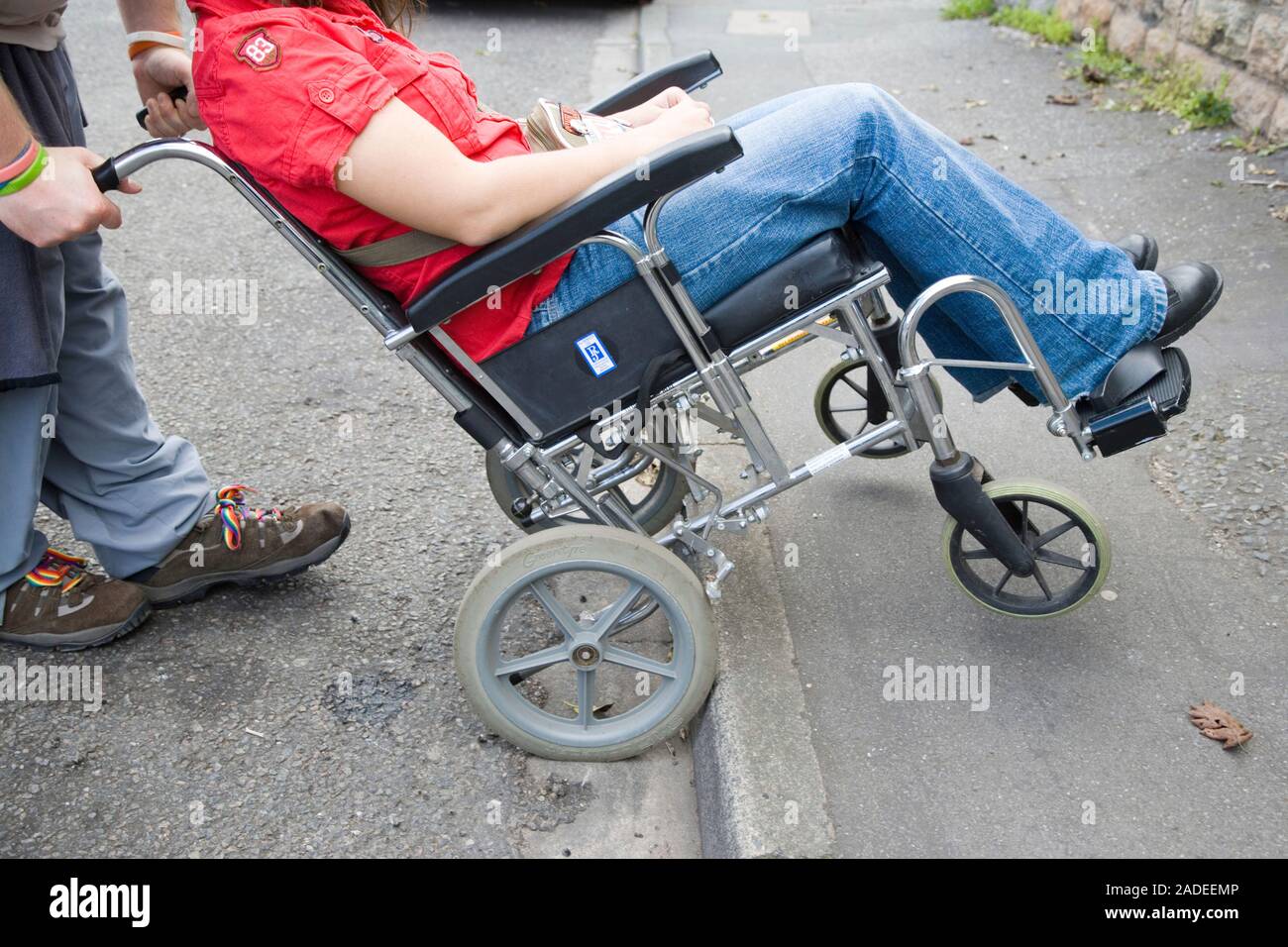 Man pushing young woman with cerebral palsy in a wheelchair up a curb