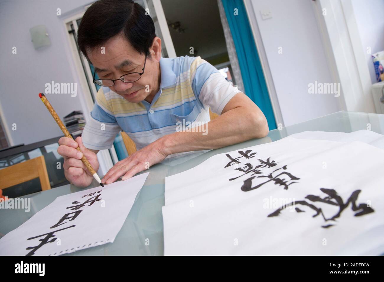 Man doing Chinese art writing using brush pen. Stock Photo