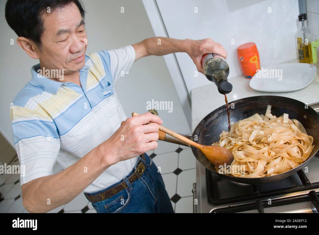 Man adding soy sauce to noodles Stock Photo Alamy