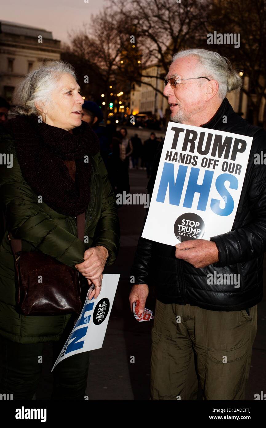 December 3rd 2019 Trafalgar Square. Anti Trump demonstration. A couple hold placards telling Trump to leave NHS alone Stock Photo