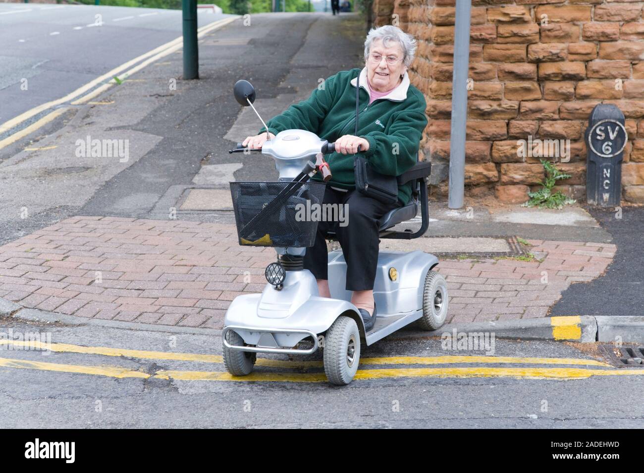 Older woman navigating a road kerb in an electric mobility scooter