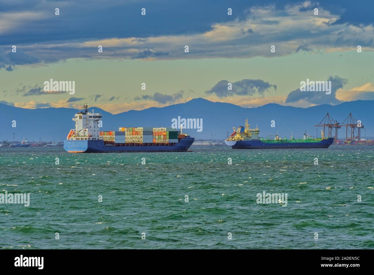 Sea transportation dry cargo vessels moored on sea with waves. Freighter merchant bulk ship & container carriers outside port of Thessaloniki, Greece. Stock Photo