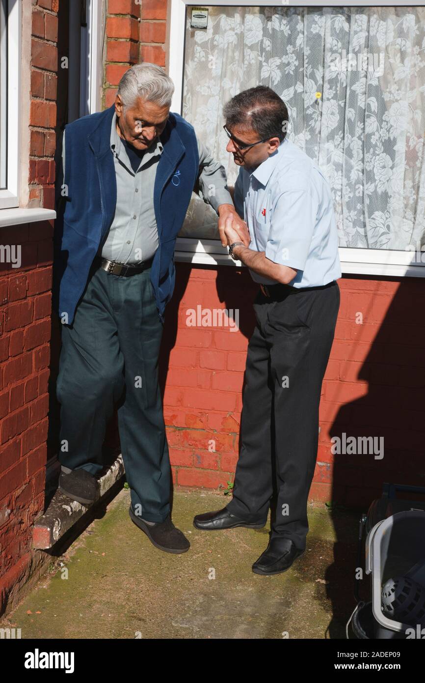 Son helping elderly south Asian father down step. Stock Photo