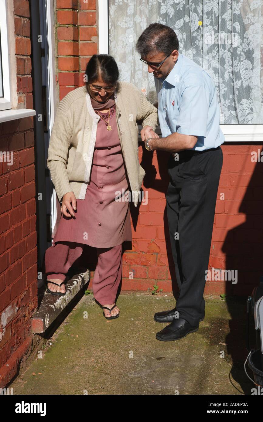 Son helping elderly south Asian mother down step. Stock Photo