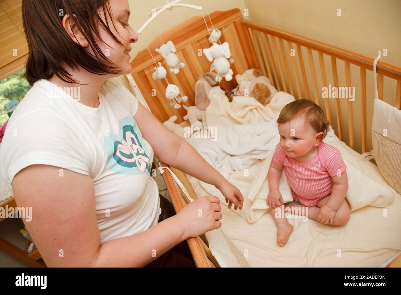 Mother putting baby into cot Stock Photo Alamy