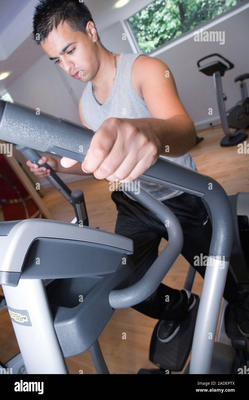 Young man using the crosstrainer at gym. Stock Photo