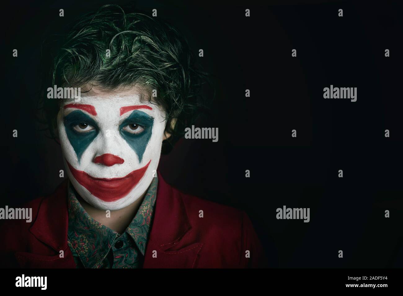 boy dressed as Joker on dark background Stock Photo