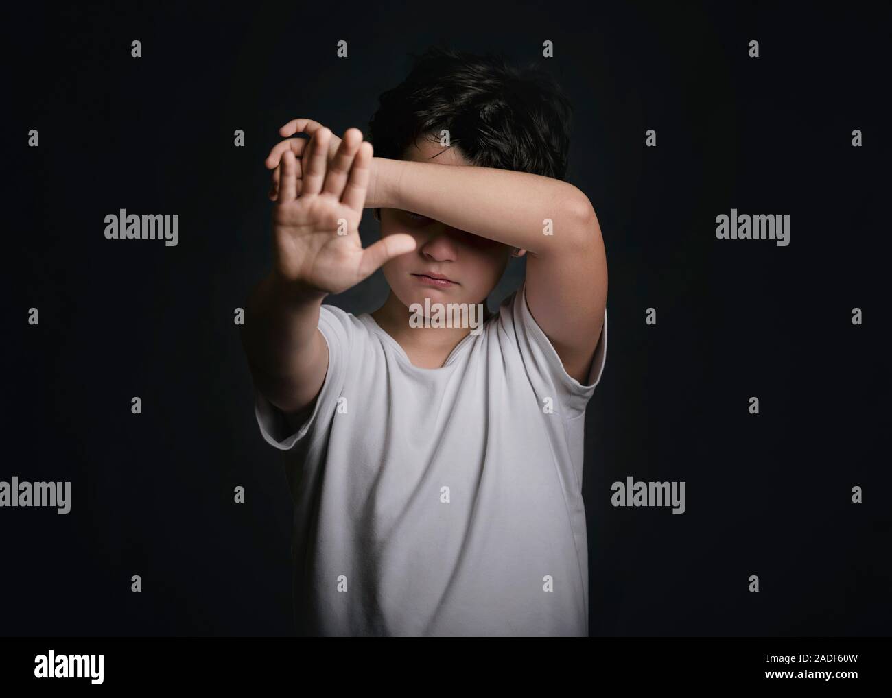 crying child showing a stop sign on black background Stock Photo