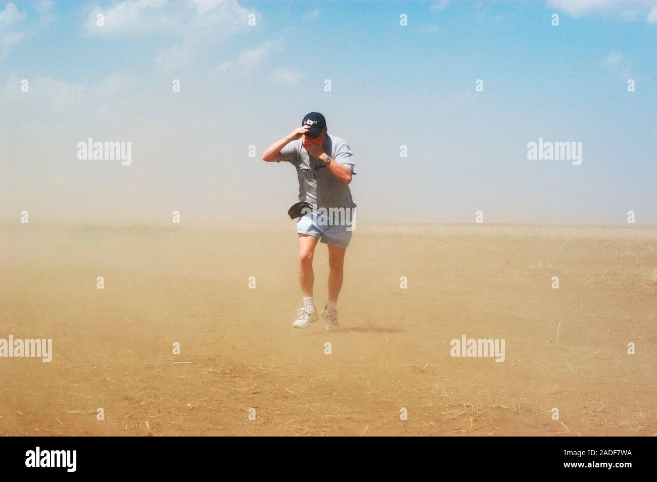 Dust storm. Man struggling to walk through a dust storm in western ...