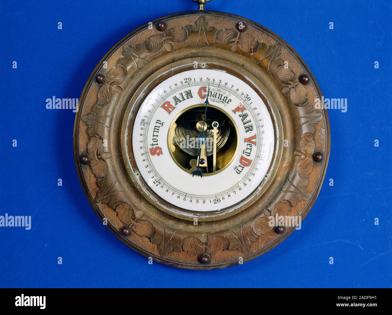 Aneroid barometer, used to measure atmospheric pressure and forecast weather. The barometer is displaying a reading of around 29.3 inches of mercury, Stock Photo