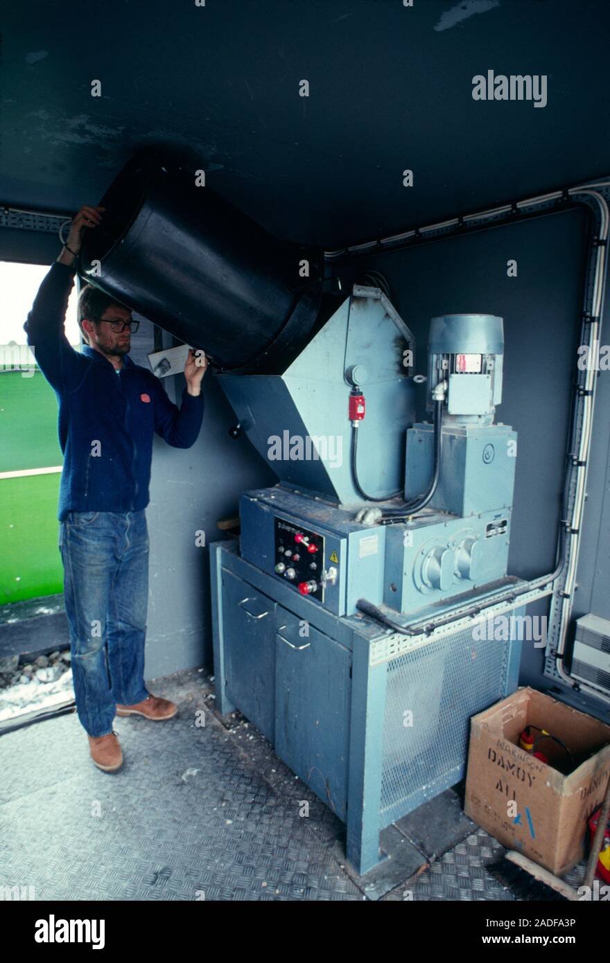 Antarctic waste disposal. Antarctic researcher putting waste into a shredder for removal from