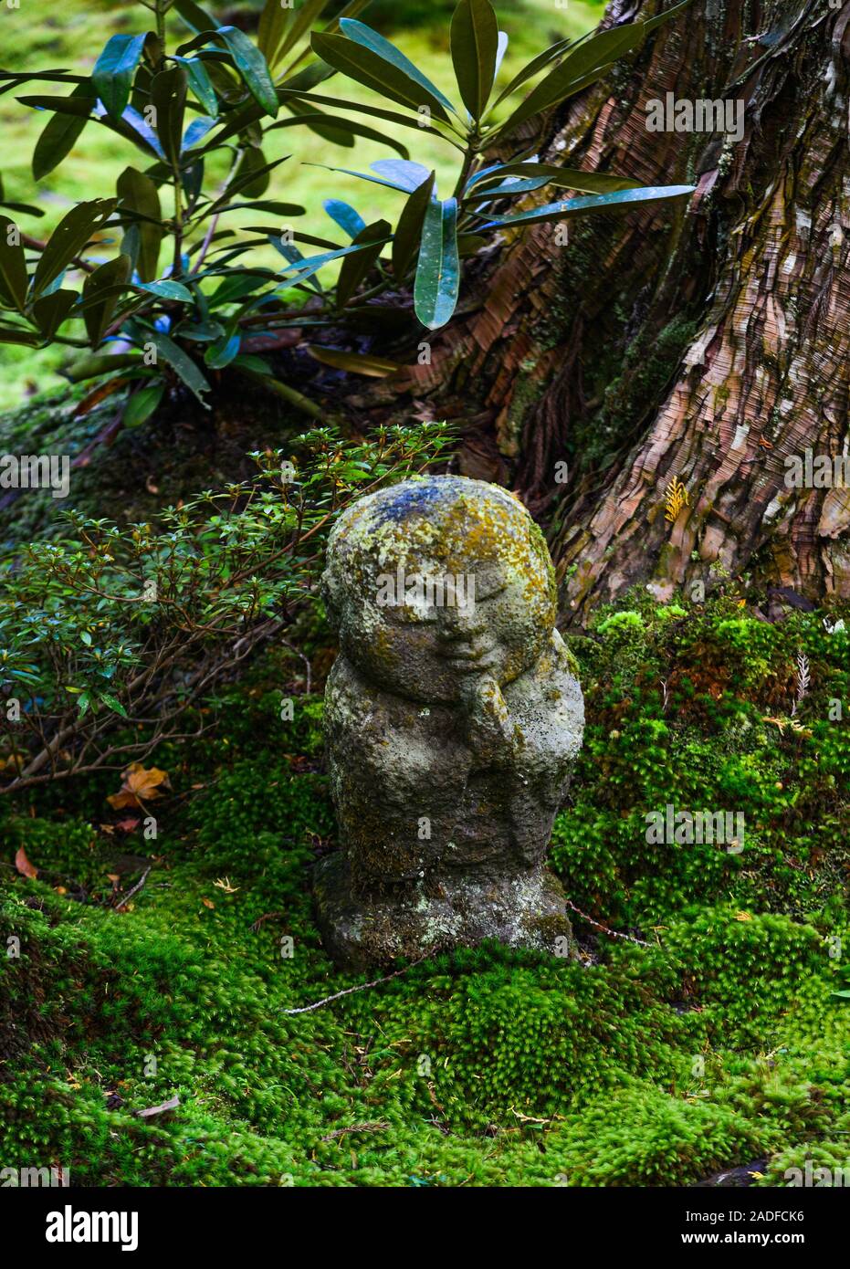 Stone statues of smiling Jizo Bosatsu with green moss at zen garden in Sanzenin Temple, Kyoto