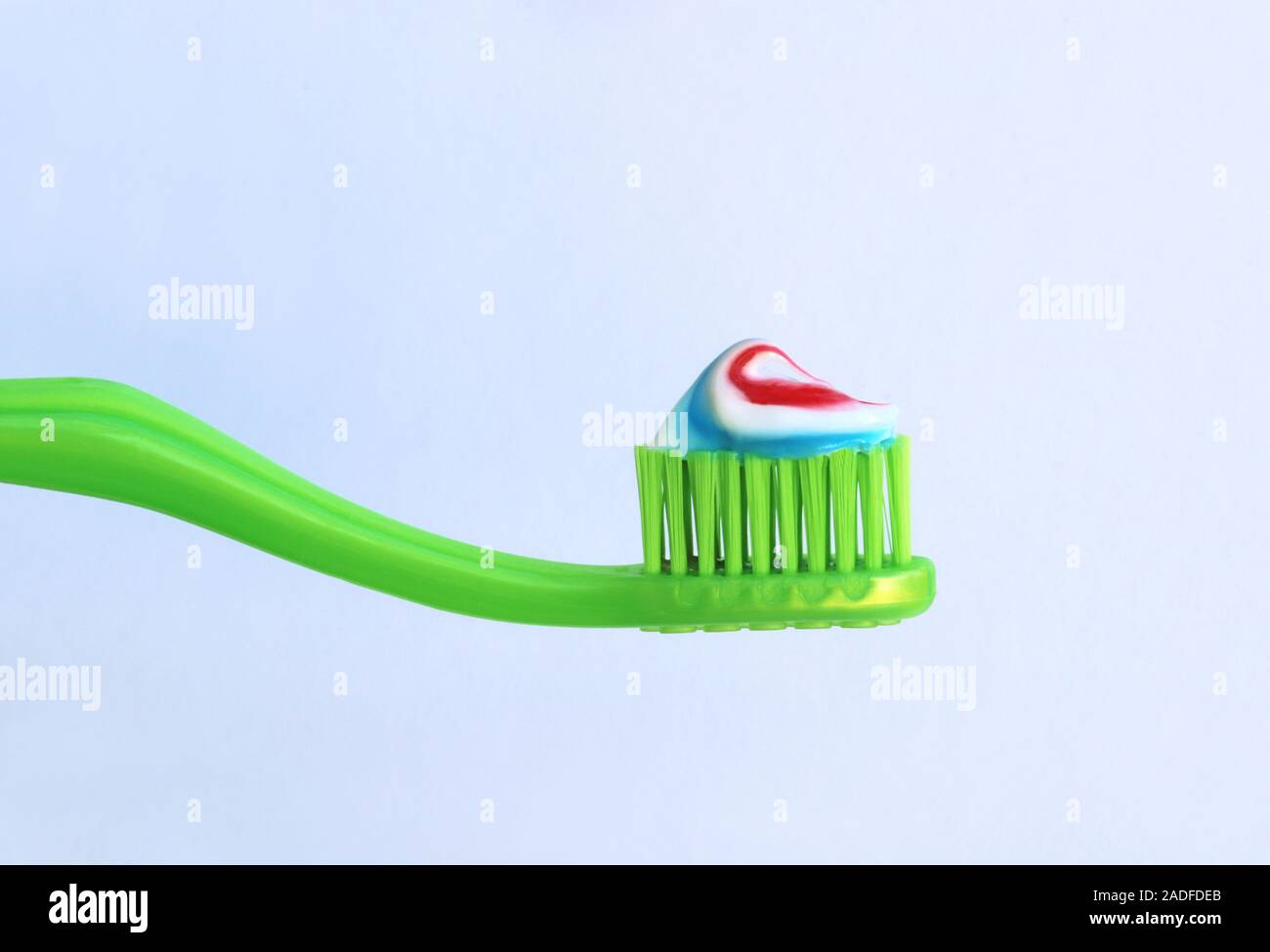 close-up of a green toothbrush with striped toothpaste in front of a ...