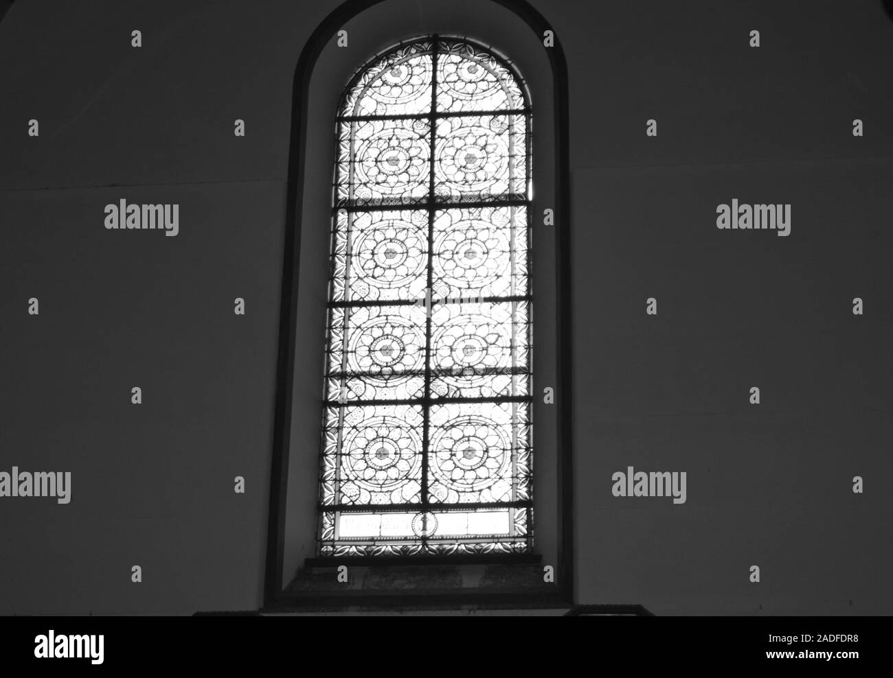 Black and white photo of stained glass in the Church against a dark wall, the interior of the Catholic Cathedral Stock Photo