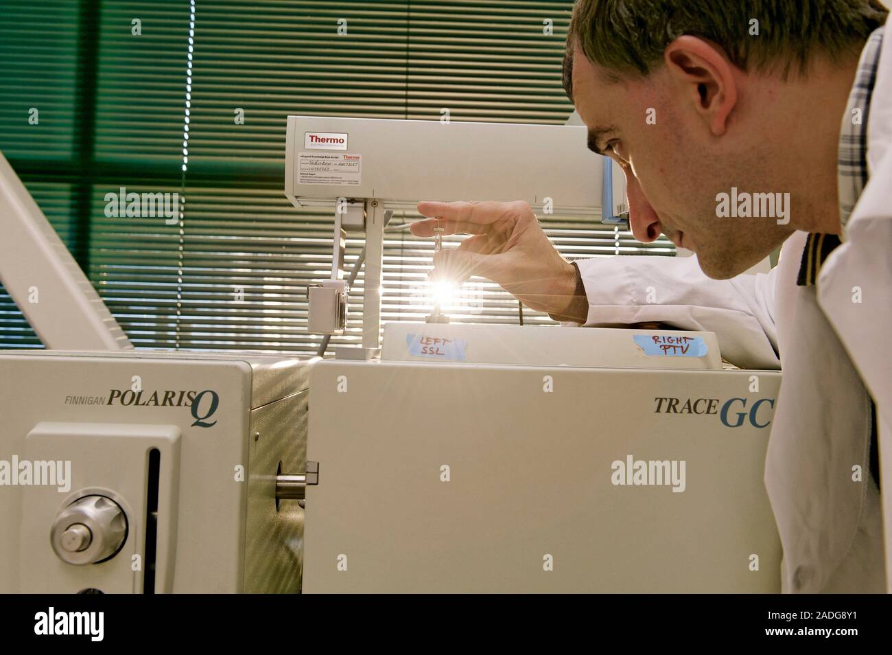 Loading Sample Into Gc Machine Gas chromatography-mass spectrometry. Researcher injecting a liquid ...