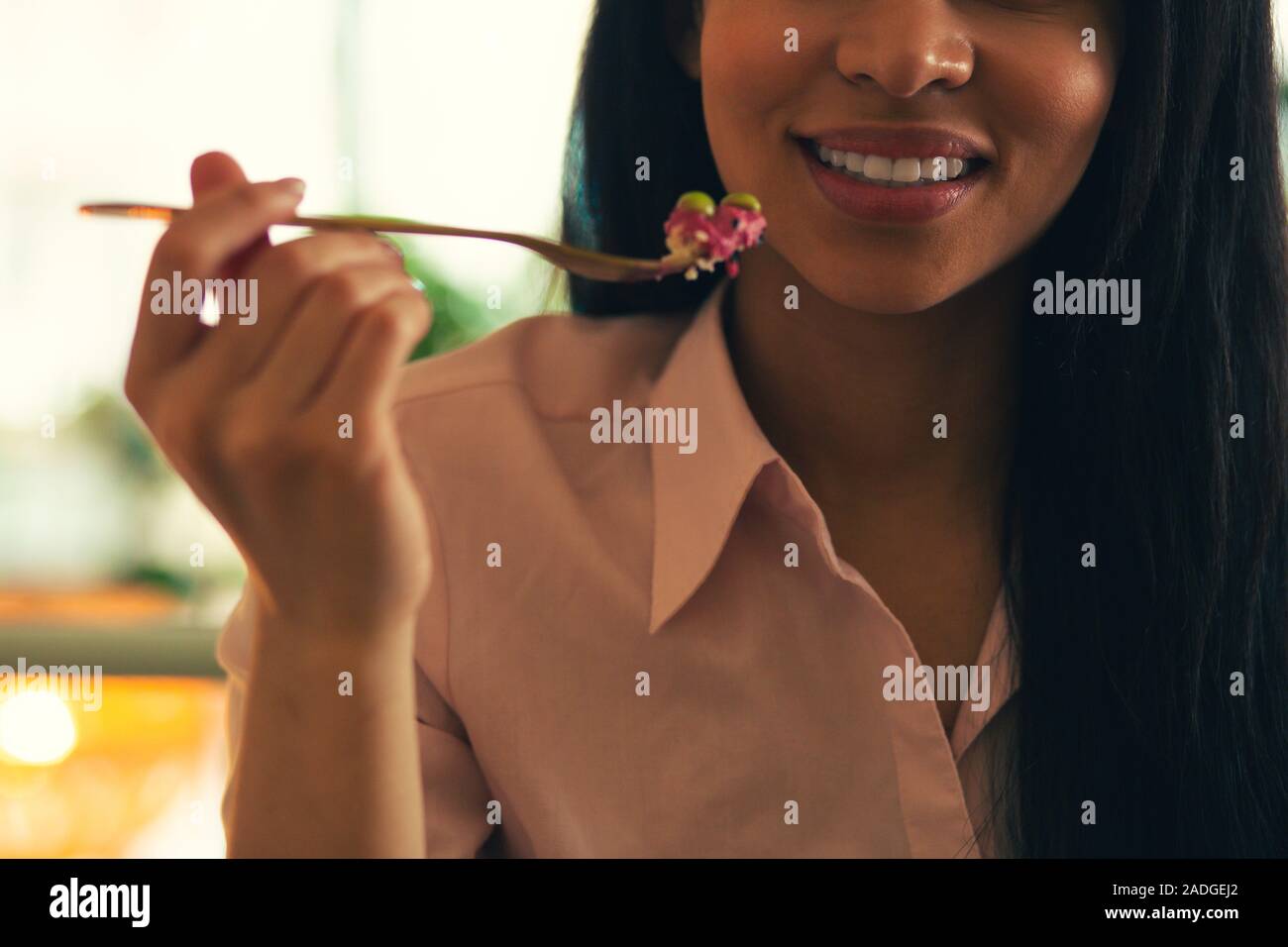 Fork with food near the face of smiling lady Stock Photo