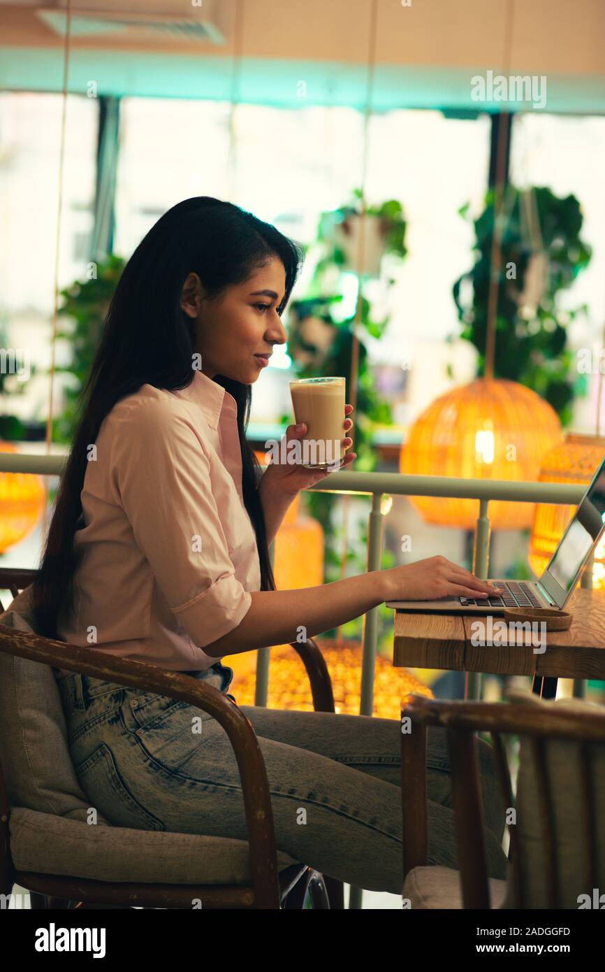Calm student using laptop and drinking latte Stock Photo