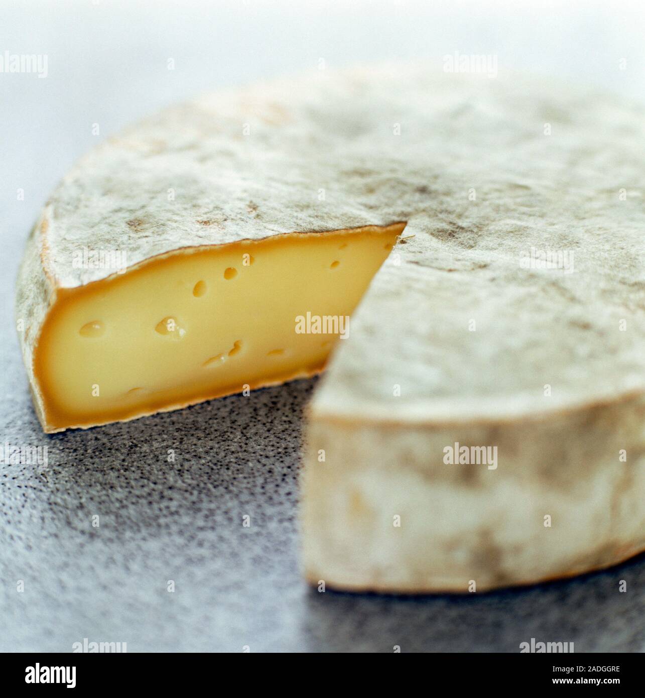 Camembert cheese with a slice cut out of it. Camambert is a French