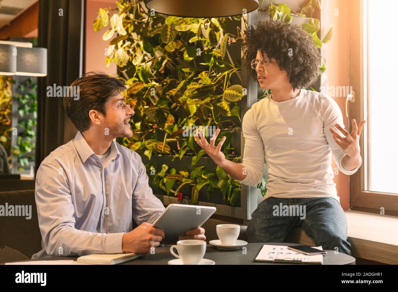 Male partners talking about business plan during coffee break Stock Photo