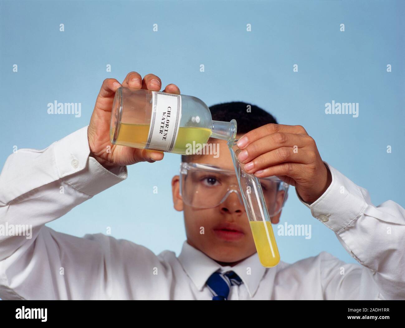 Displacement reaction. Student pouring chlorine water into a test tube