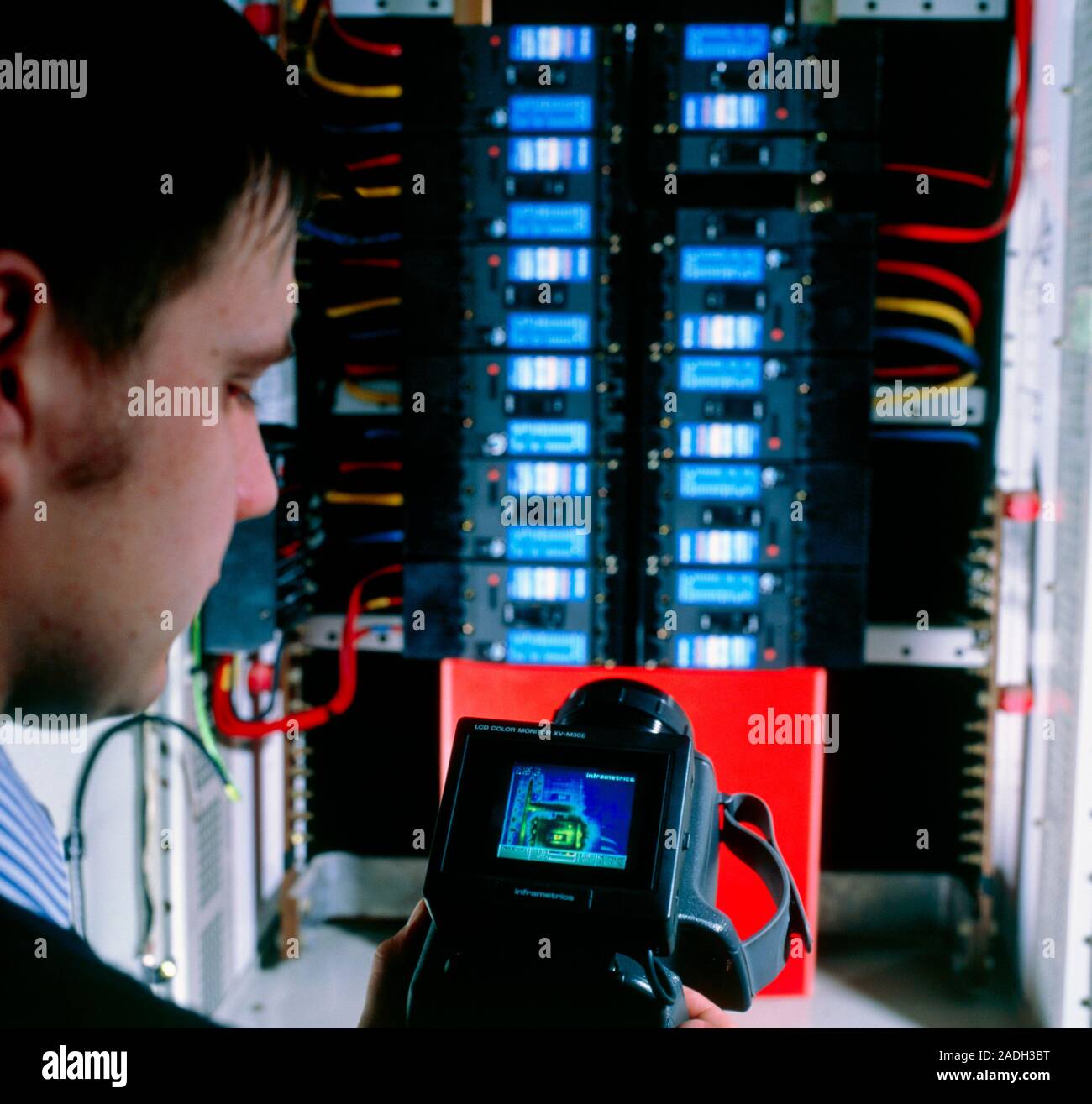 Thermal imaging camera. Technician using a thermal imaging camera to study the temperature of a stack of electronic circuits. Hotter areas are represe Stock Photo