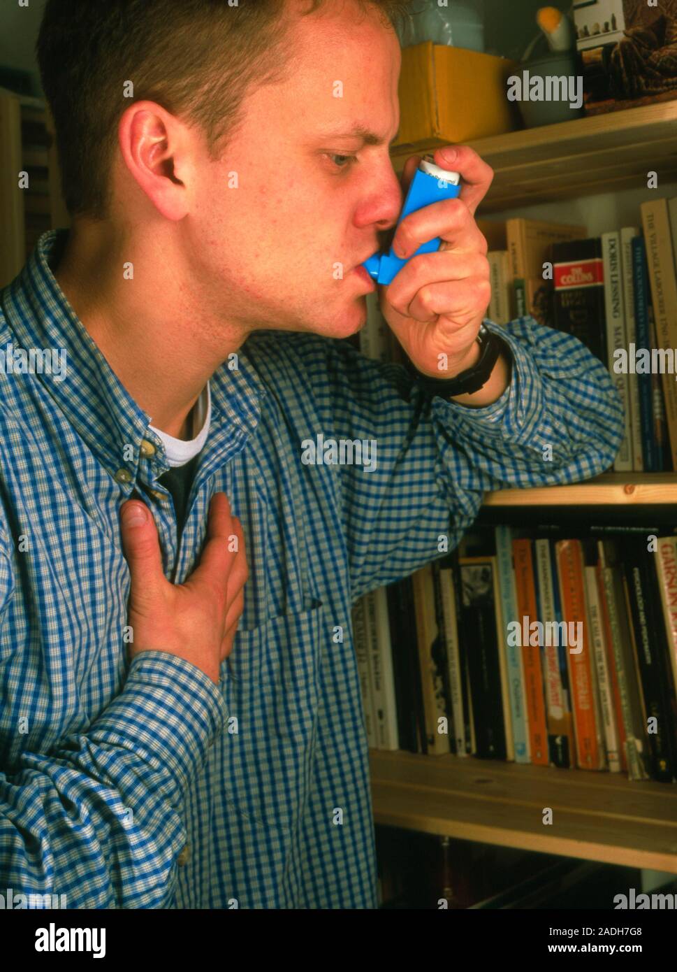 Asthma relief. Young man using an inhaler to control an asthma attack