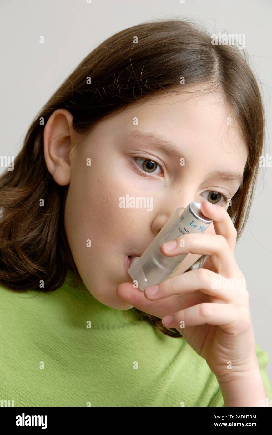MODEL RELEASED. Girl using an inhaler to treat an asthma attack. The