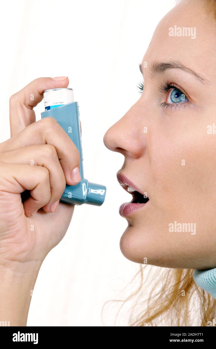 Woman using an inhaler to treat an asthma attack. The inhaler contains bronchodilator drugs that
