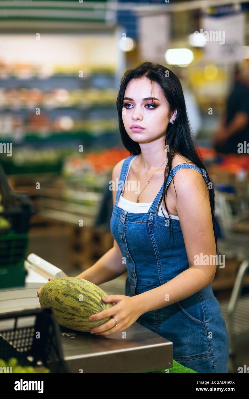 Buyer weighs melon on electronic scales in a supermarket. Healthy food Stock Photo