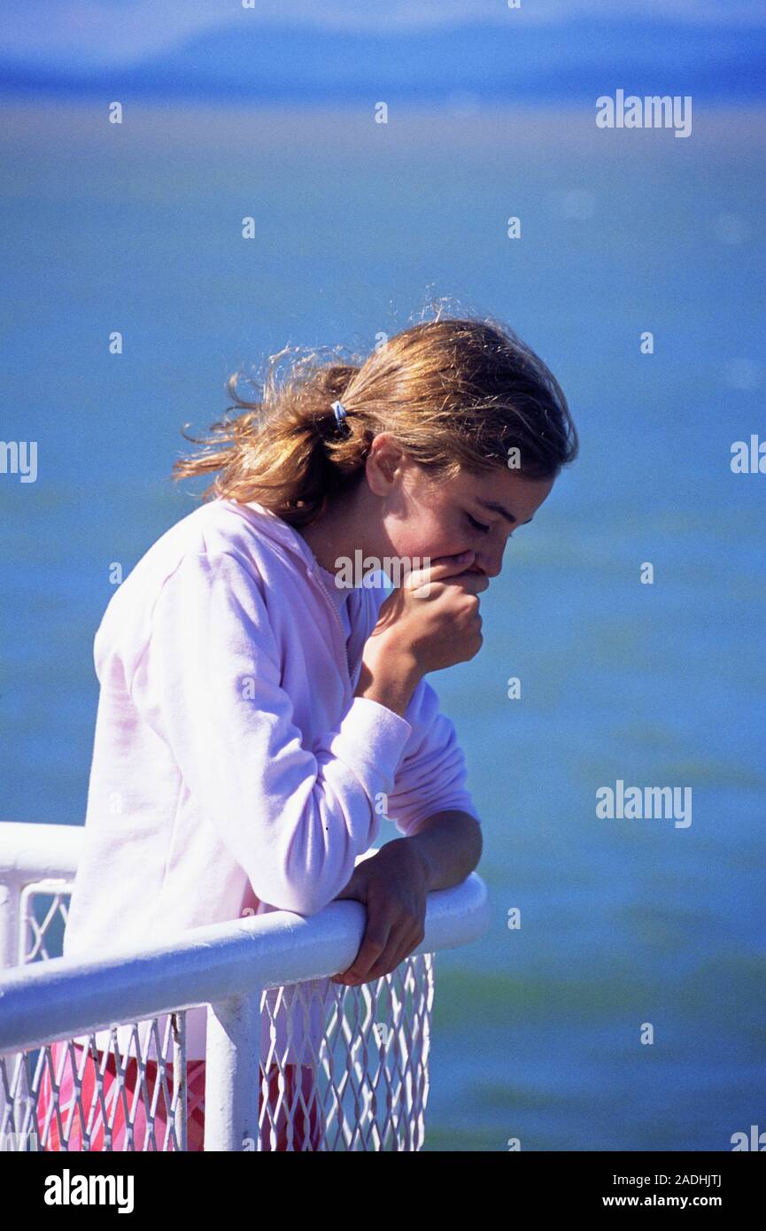 Seasickness. Teenaged girl leaning over the edge of a boat. She is