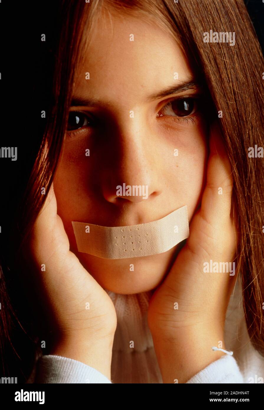 Autism. Girl with tape over her mouth and covering her ears in a