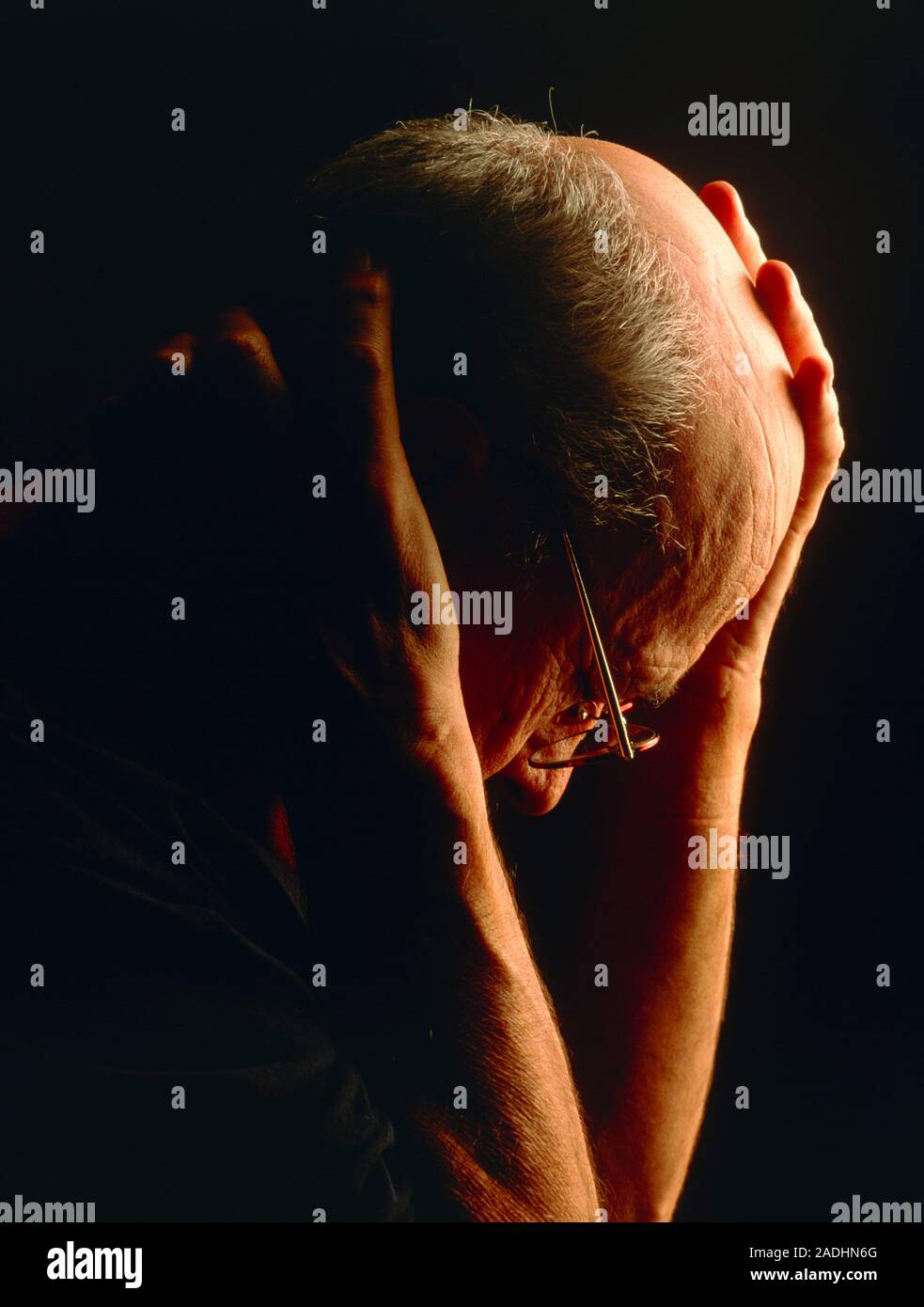 MODEL RELEASED. Depression. Elderly man holding his hands to his head ...