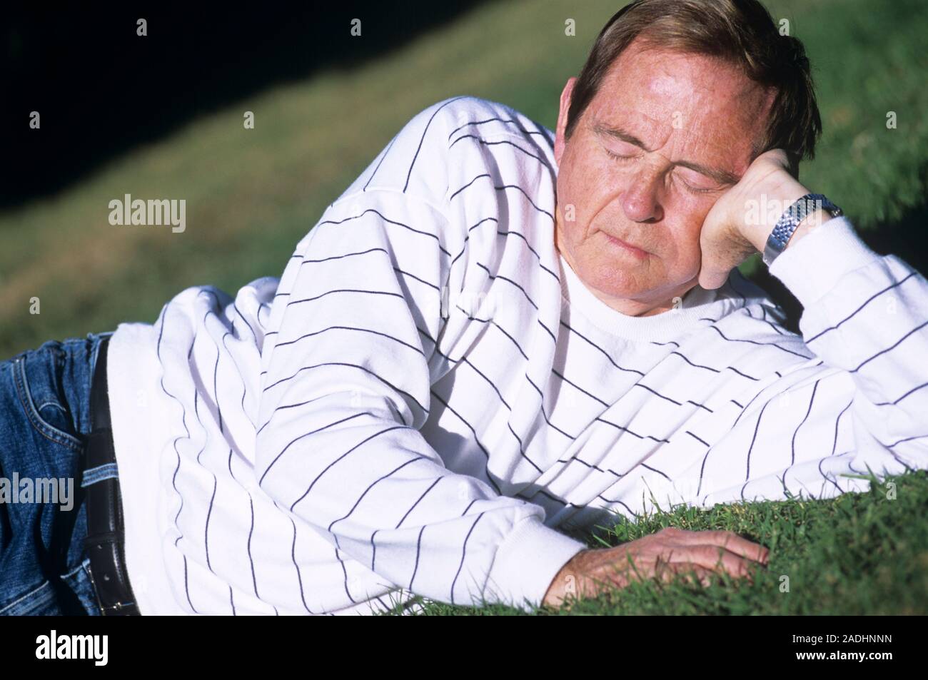 MODEL RELEASED. Relaxed man lying down on grass. Stock Photo