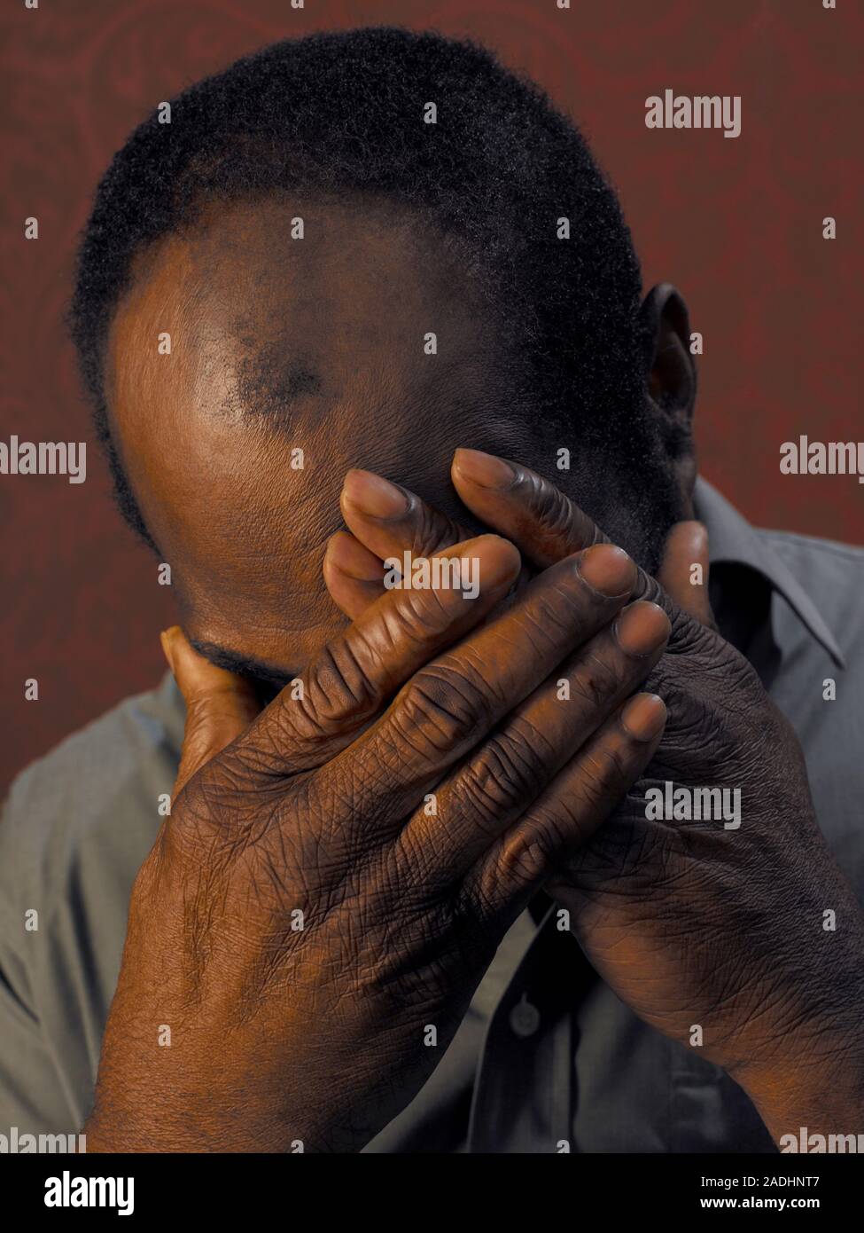 MODEL RELEASED. Depressed man cupping his face in his hands Stock Photo