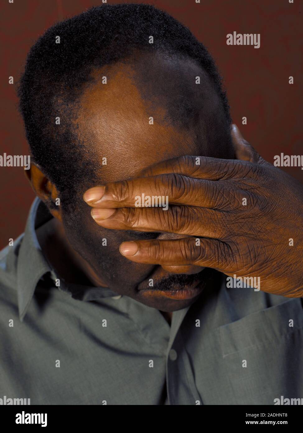 MODEL RELEASED. Depressed man cupping his face in his hands Stock Photo
