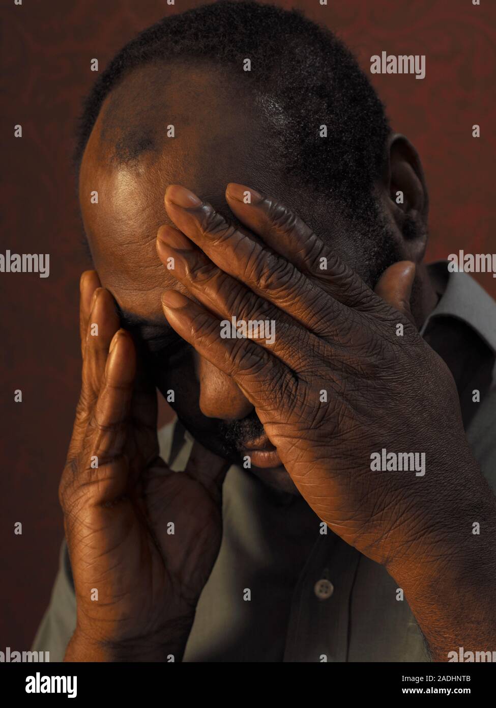 MODEL RELEASED. Depressed man cupping his face in his hands Stock Photo