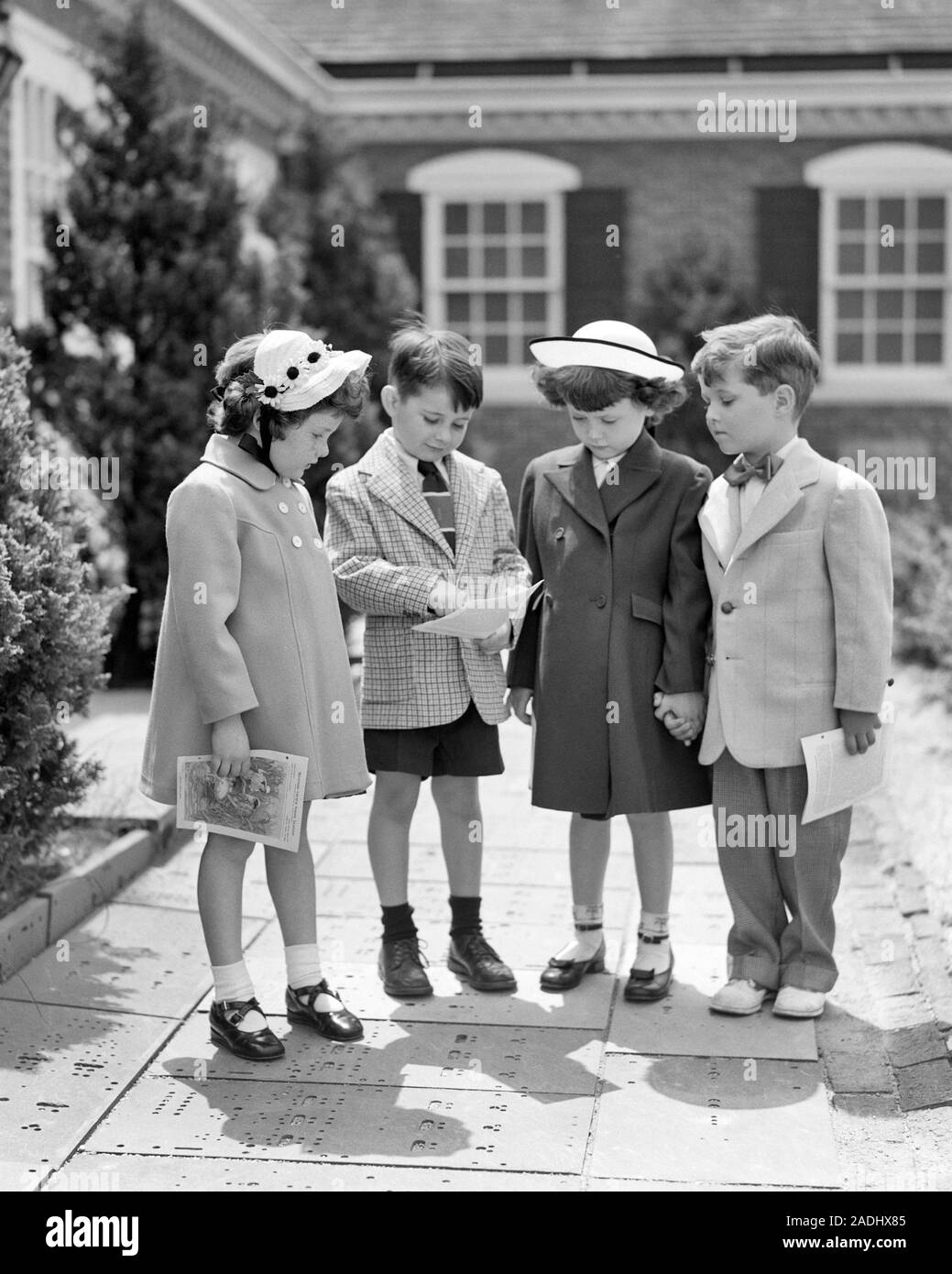 1950s BOYS AND GIRLS DRESSED IN SUNDAY BEST CLOTHES GOING OVER SUNDAY SCHOOL PROGRAM STANDING IN FRONT OF CHURCH BUILDING - c3988 HAR001 HARS BEST JOY LIFESTYLE SATISFACTION RELIGION FEMALES EASTER SUNDAY BROTHERS COPY SPACE FRIENDSHIP FULL-LENGTH INSPIRATION FESTIVAL MALES CHRISTIAN SIBLINGS SPIRITUALITY CONFIDENCE SISTERS B&W SUIT AND TIE HIGH ANGLE RELIGIOUS AND CHRISTIANITY EXTERIOR EASTER BONNET SIBLING CONNECTION STYLISH SUNDAY BEST FAITHFUL COOPERATION FAITH GROWTH JUVENILES PROGRAM SPIRITUAL TOGETHERNESS BELIEF BLACK AND WHITE CAUCASIAN ETHNICITY HAR001 INSPIRATIONAL OLD FASHIONED Stock Photo