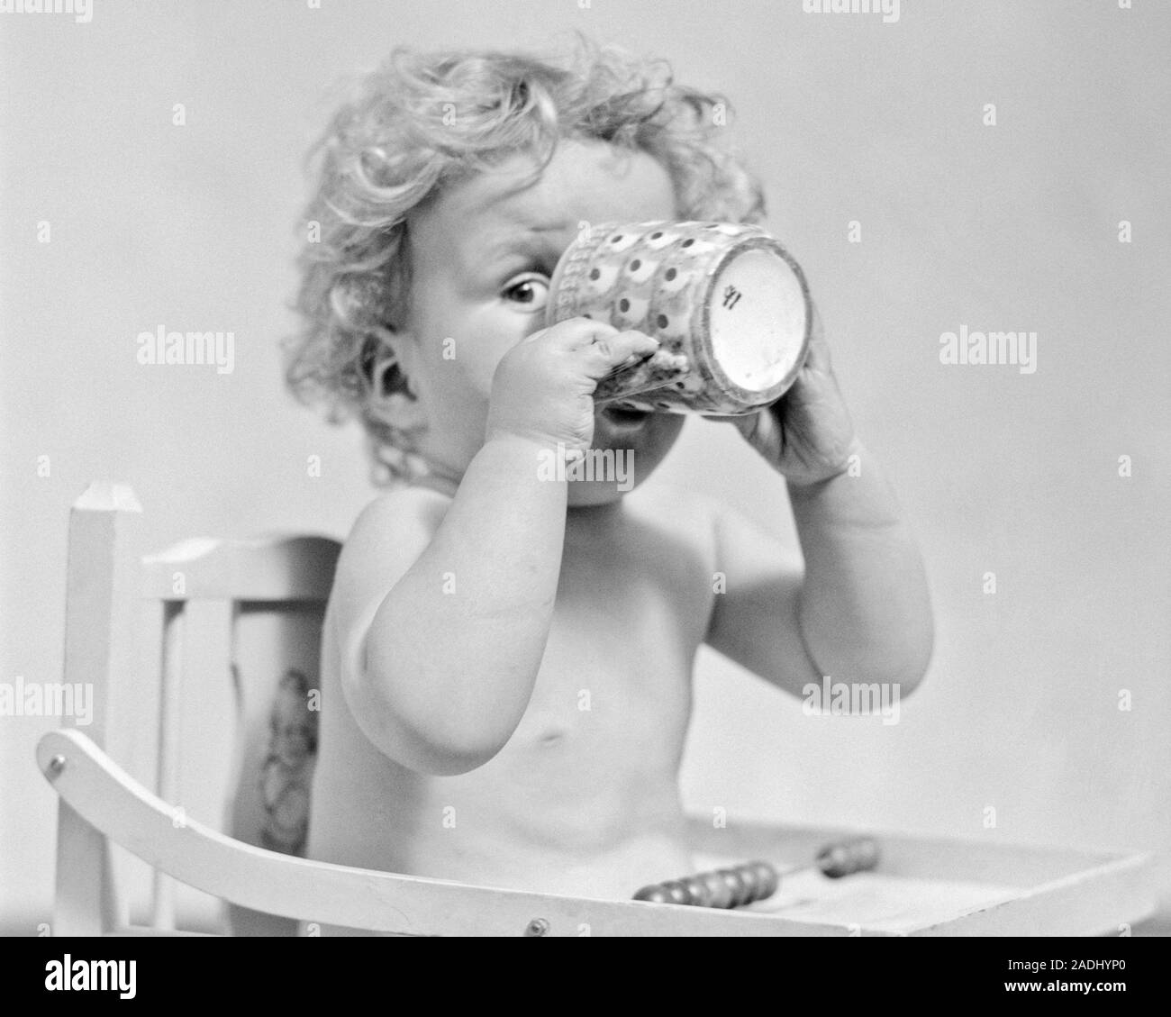 1930s Baby Boy Sitting In High Hair Drinking From Mug Covering Most Of His Face Peeking Out With One Eye Looking At Camera F4798 Har001 Hars Dairy Copy Space Half Length Males 1930s Baby Boy Sitting In High Hair Drinking From Mug Covering Most Of His Face Peeking Out With One Eye Looking At Camera F4798 Har001 Hars Dairy Copy Space Half Length Males