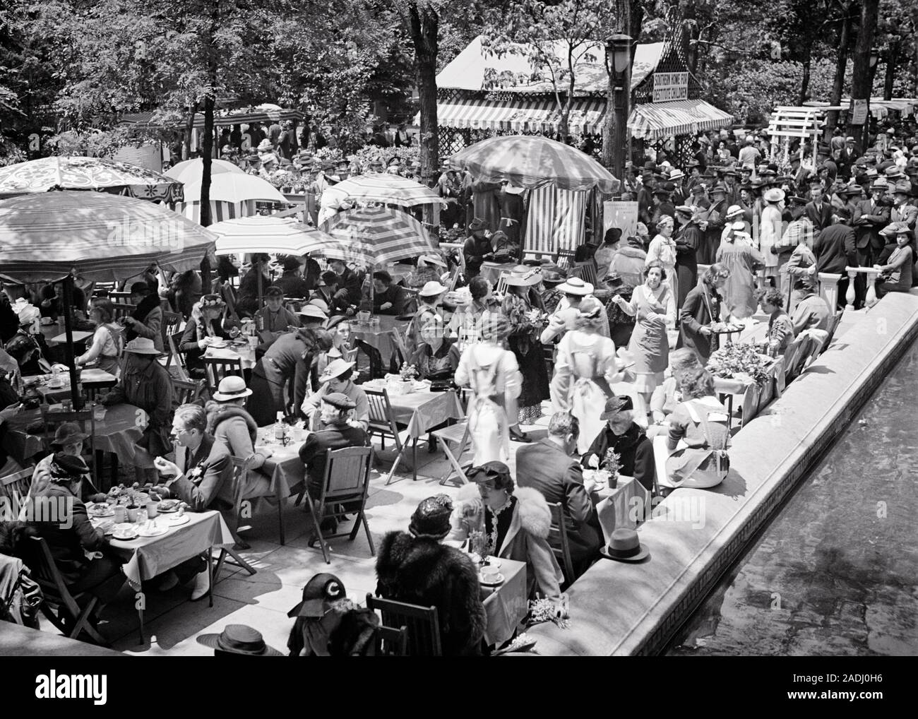 1930s CROWDED TABLES OF STYLISH MEN AND WOMEN EATING LUNCH ALFRESCO DURING RITTENHOUSE SQUARE FLOWER MARKET PHILADELPHIA PA USA - f7810 HAR001 HARS FRIENDSHIP LADIES PERSONS MALES SENIOR ADULT B&W PARTNER TABLES HAPPINESS HIGH ANGLE LEISURE AND EXTERIOR LEADERSHIP PA POWERFUL RECREATION PRIDE OF AUTHORITY RITTENHOUSE SQUARE CONCEPTUAL STYLISH UPPER CRUST MID-ADULT SPRINGTIME WELL-TO-DO WIVES BLACK AND WHITE CAUCASIAN ETHNICITY DURING HAR001 OLD FASHIONED Stock Photo
