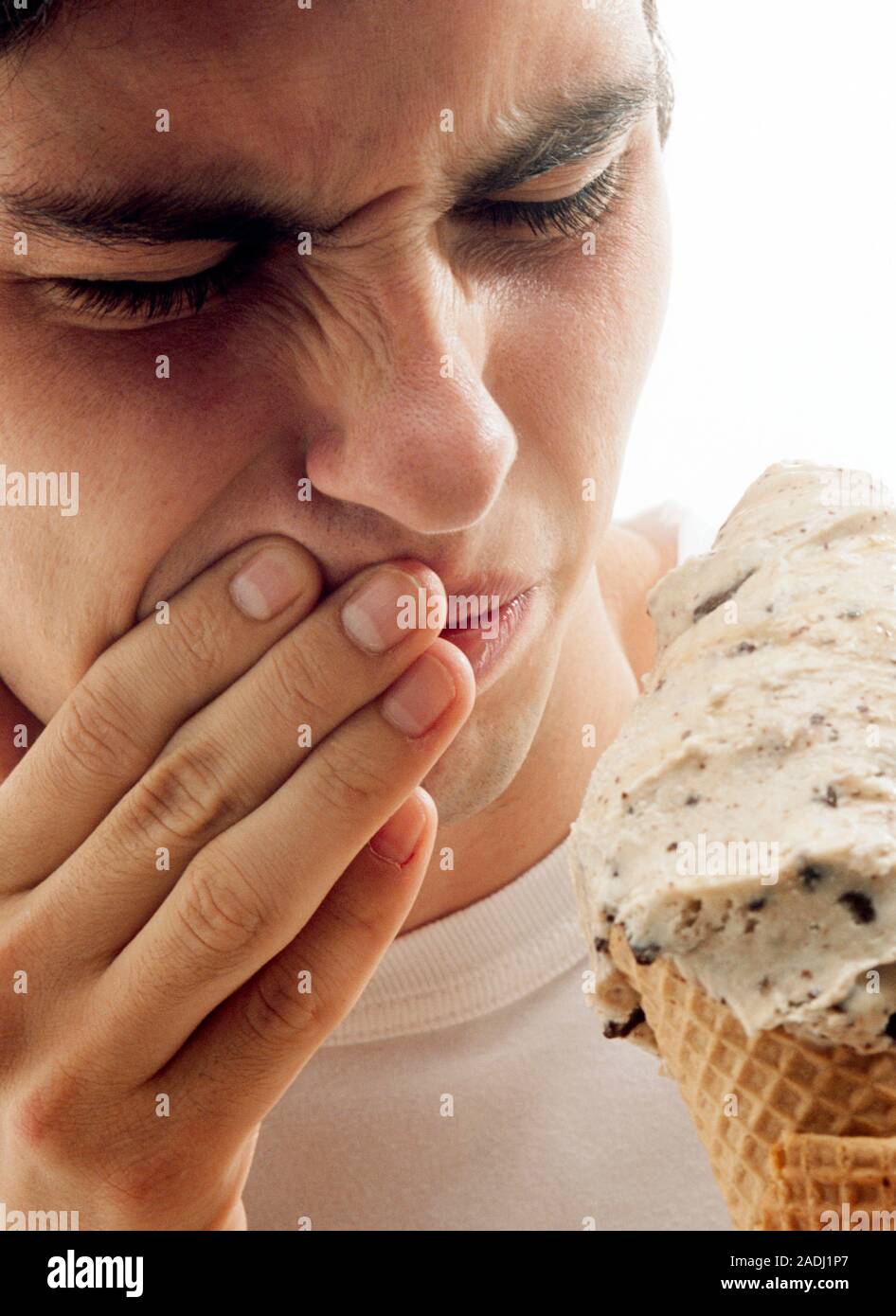 MODEL RELEASED. Tooth pain. Man wincing in pain after eating ice cream